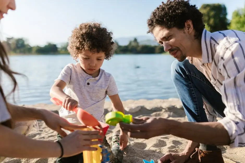 Ibu mengamati anak bermain dengan pasir di pantai Tarempa